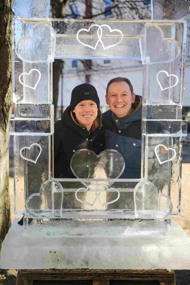 A couple poses behind an ice sculpture of a picture frame at Salem’s So Sweet Chocolate & Ice Sculpture Festival in Salem, Massachsuetts.