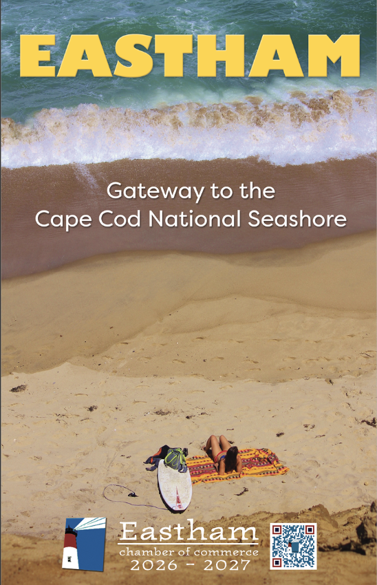 A person relaxes on a beach towel next to a surfboard and a bag on sandy shore, with waves crashing nearby. Text reads: EASTHAM, Gateway to the Cape Cod National Seashore. Chamber of Commerce info is at the bottom.