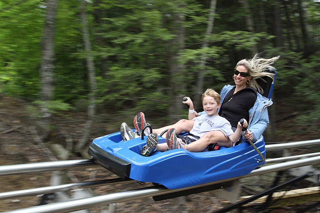A child and mother ride an alpine roller coaster.