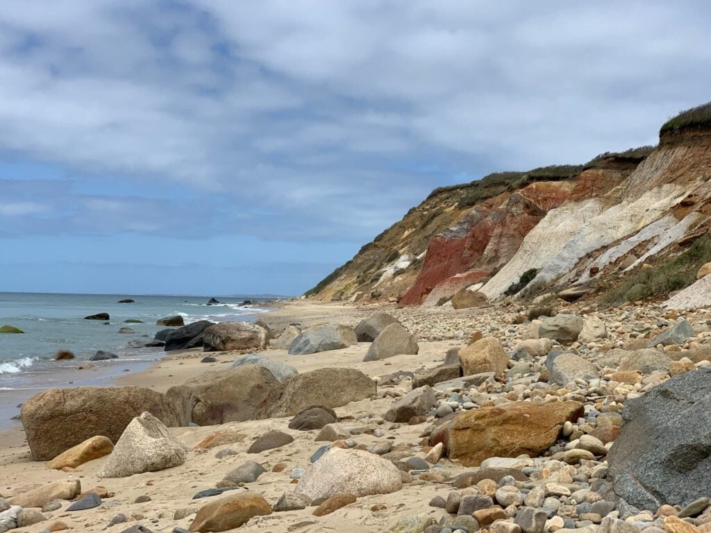 A rocky cliff against a sandy beach.