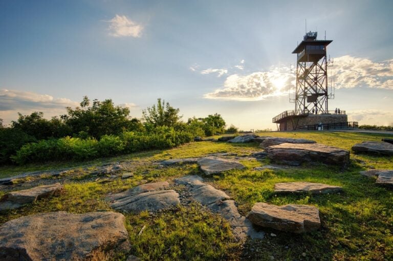 The sun rises above a watchtower on a mountain top.