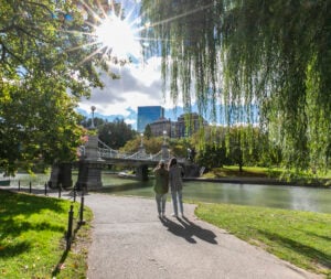 Pedestrians walk in the Boston Public Garden on a sunny day.