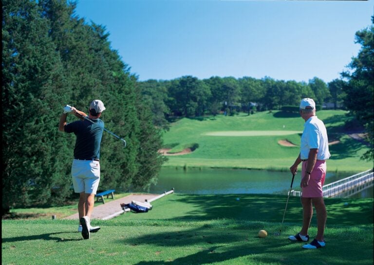 Golfers tee off on a sunny day.