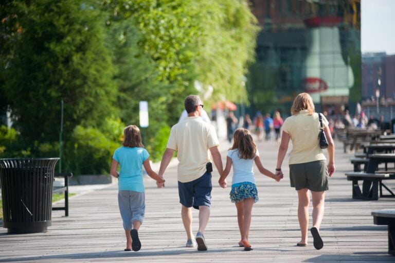 A family walks along a wooden boardwalk in Boston.