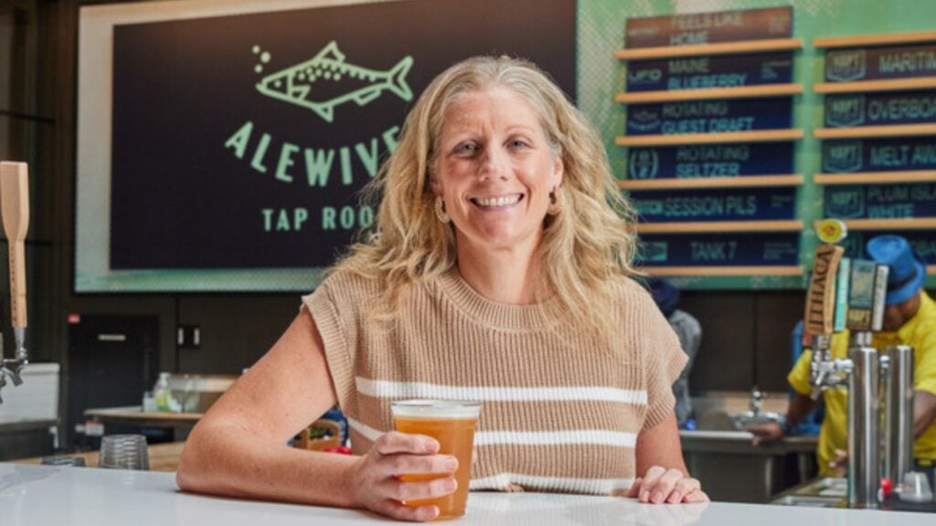 A woman sits inside of a tap room.