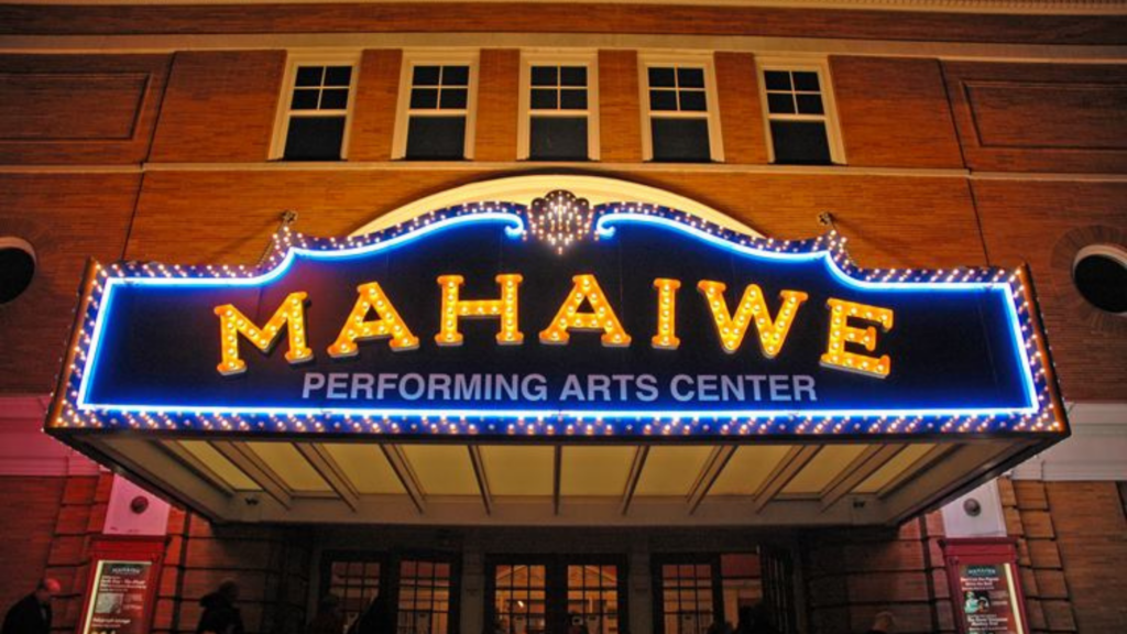 A lit marquee sign reading "MAHAIWE PERFORMING ARTS CENTER" outside of a red brick building in Great Barrington, Massachusetts.