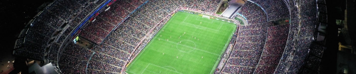 A soccer game takes place on a field in front of hundreds of spectators.