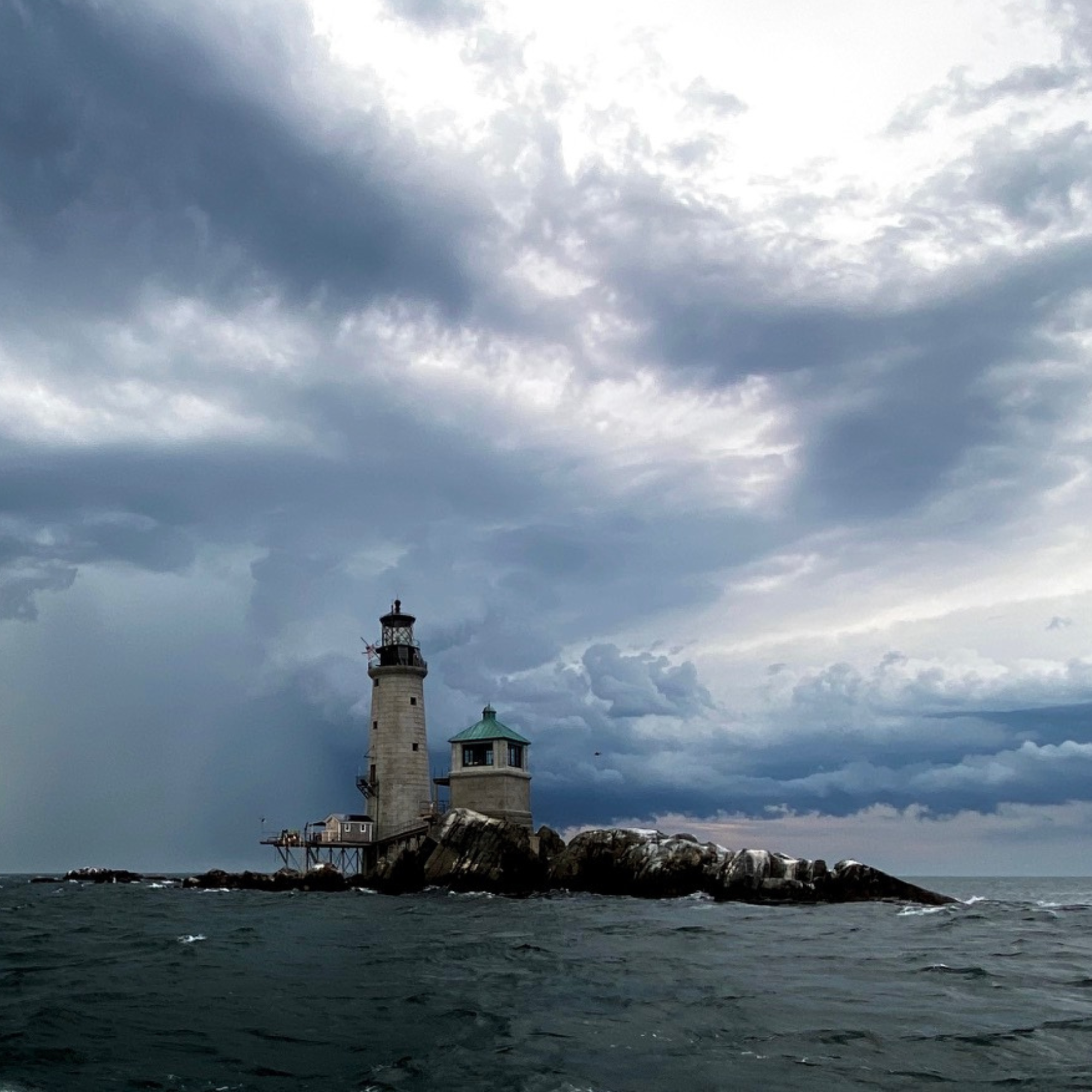 Graves Light in Boston Harbor against a cloudy blue sky.