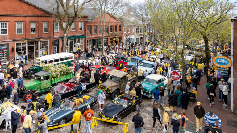 A parade of antique cars and festival attendees fill the cobblestone streets on Nantucket.