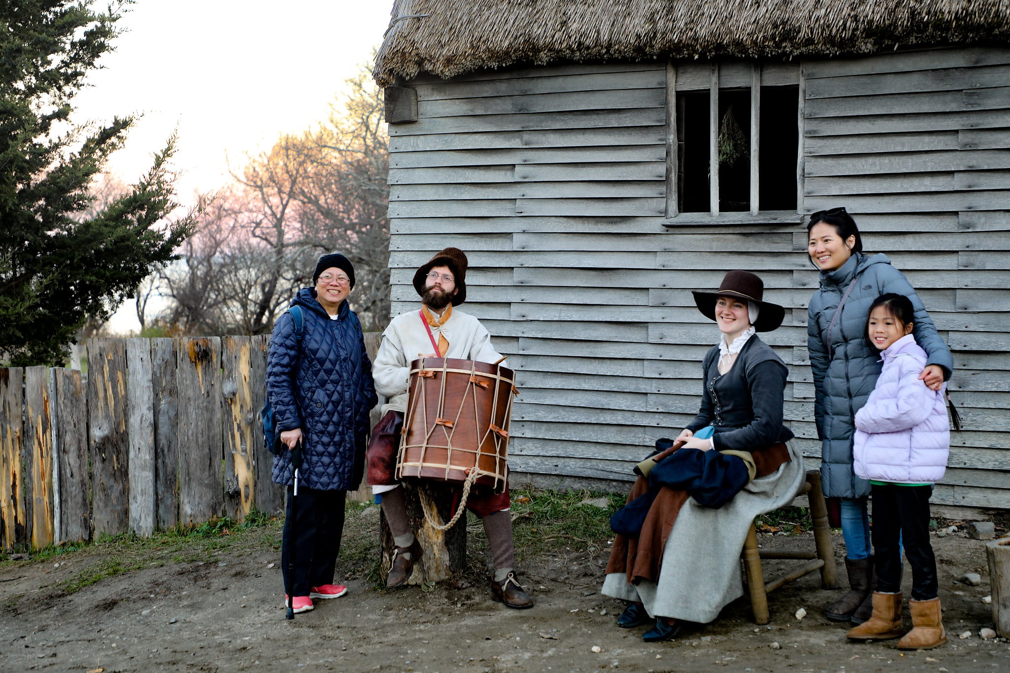 A family poses with pilgrim reenactors outdoors.