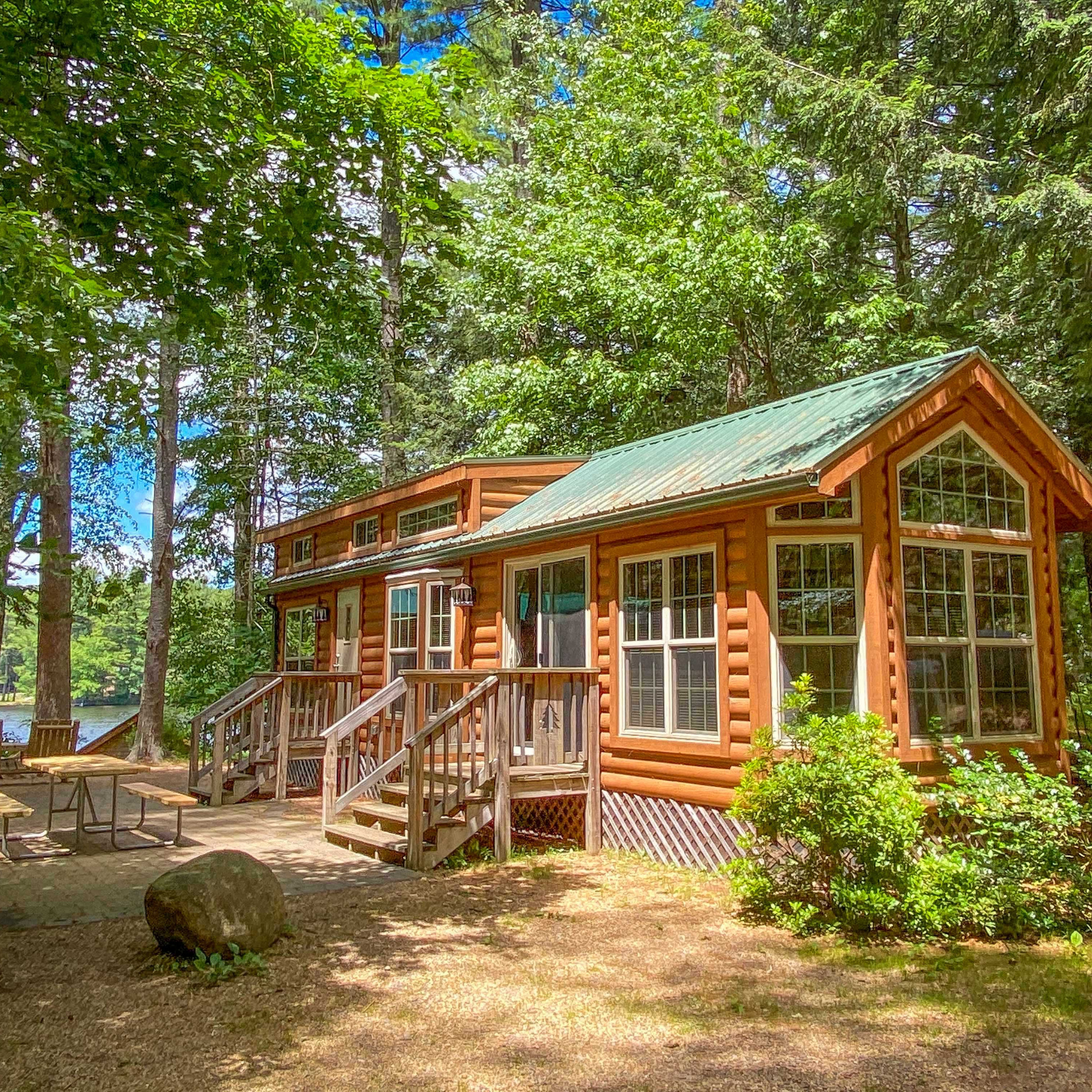 A wooden cabin underneath green trees.