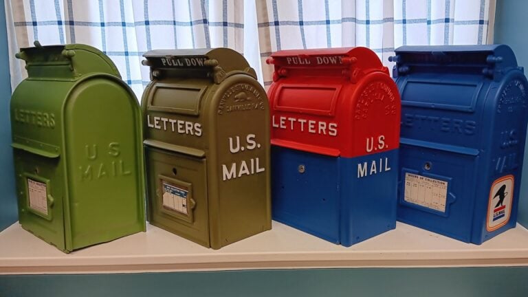 A row of antique mailboxes lined up on a shelf.