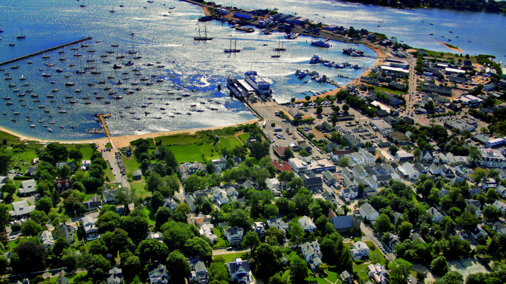 A drone shot of Vineyard Haven Harbor - boats floating on blue water with buildings dotting the coast.