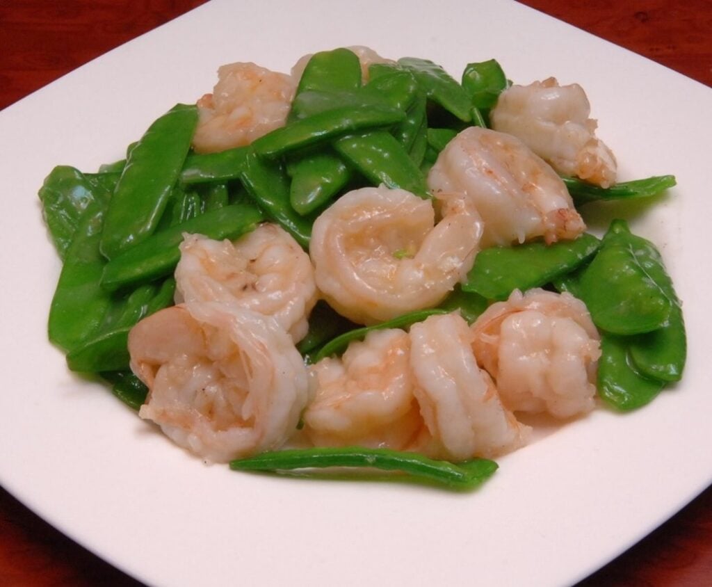 A plate of cooked shrimp with peapods